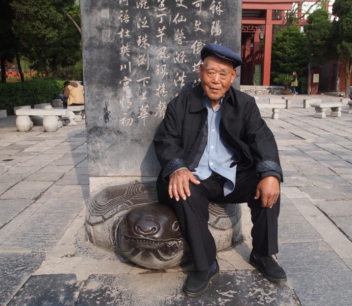 a kindly Chinese gentleman sits on a stele